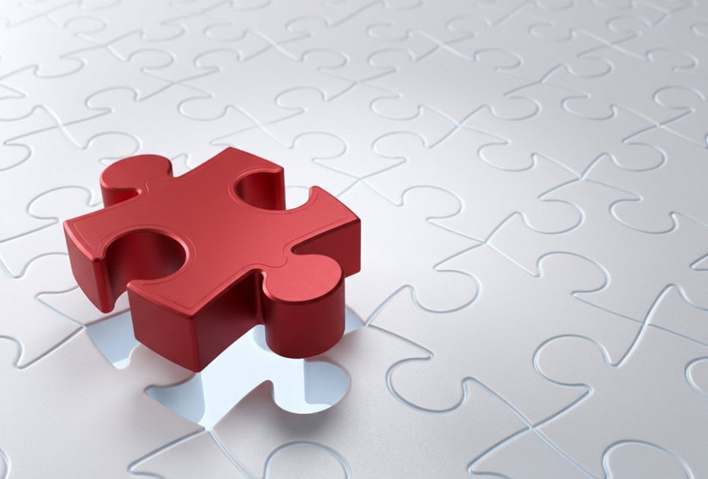 Rotes Puzzleteil, das auf einer Fl&auml;che aus vielen ineinandergreifenden wei&szlig;en Puzzleteilen liegt. Das Motiv steht sinnbildlich f&uuml;r Zusammenhalt, Vernetzung und den Beitrag jedes einzelnen Partners zu einem starken gemeinsamen Netzwerk.